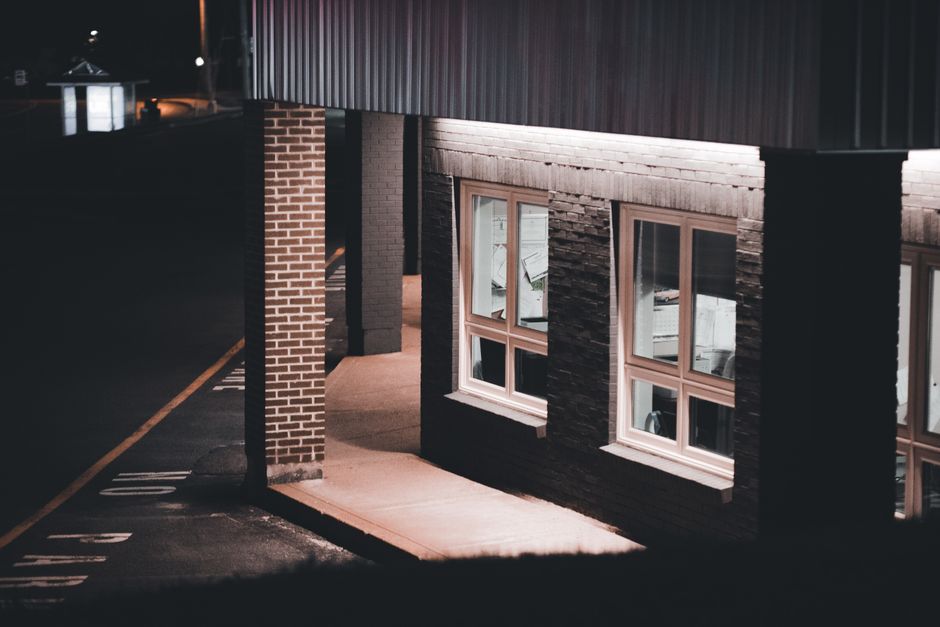 Security guard checking a locked commercial door with a flashlight during an alarm response at night in Surrey BC